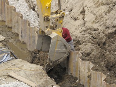 İnşaat alanındaki metal bariyerlerin yakınını kazan kazıcı