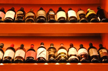 Ahşap raflarda sıralanmış şarap şişeleri.