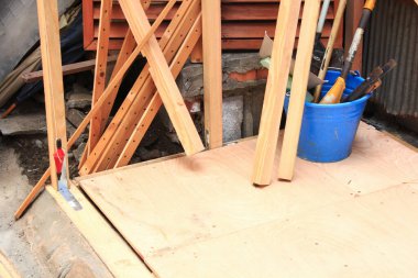 Mavi kovanın yanında duran çeşitli ahşap tahtalar.