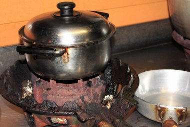 Geleneksel ocağın üzerinde alevler içinde duran metal tencere.