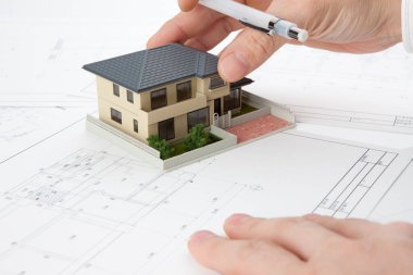Masasında ev modeli olan bir kalem tutan mimar, yakın plan görünüm             