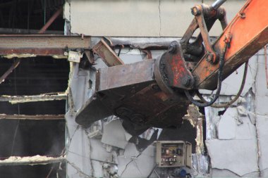 Turuncu kazıcı eski beton duvar yapısını yıkıyor