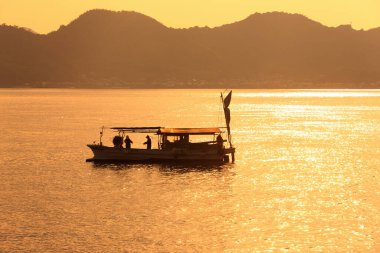 Denizde altın saatinde balıkçı teknesinin silueti