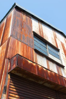 Paslı metal duvarları ve penceresi olan bir bina.