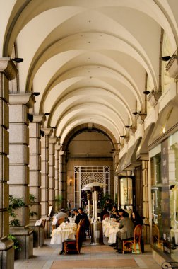 Kemerli tavan altında yemek yiyen insanlar.