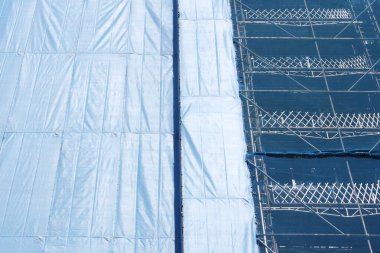 İnşaat alanındaki iskeleyi kaplayan mavi inşaat brandaları