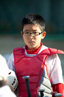 Japon çocuk sahada beyzbol oynuyor.