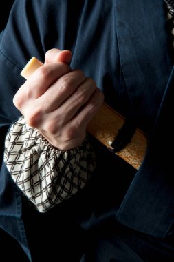 Ninja kostümlü genç adam kılıç tutuyor. 