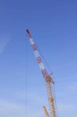 Mavi gökyüzü arka planında inşaat vincinin düşük açılı görüntüsü              