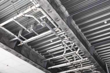 Metal borular ve çelik kirişlerle korunmasız sanayi tavanı