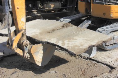 Kazı kovası inşaat sırasında beton levhayı kaldırıyor