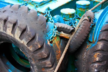 Mavi paslı teknede geniş lastikler ve ipler.