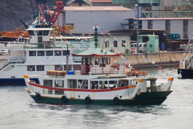 Japon Yolcu Feribotu Küçük Bayraklarla süslenmiş bir sahil iskelesine yanaşıyor.