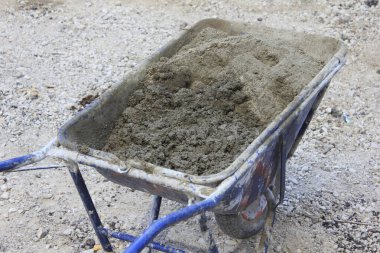 İnşaat alanında gri betonla dolu el arabası.