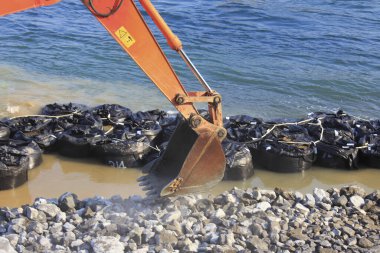 Kazıcı deniz kıyısından çöp topluyor.