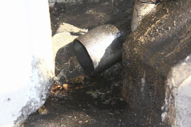 Metal boru, suyu ıslak beton yüzeye boşaltıyor.