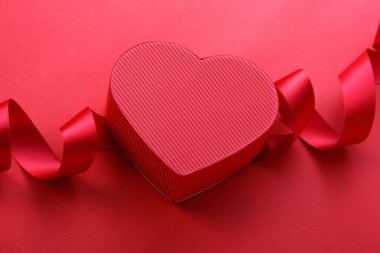 Kırmızı arka planda kurdeleli kırmızı kalp kutusu, Sevgililer Günü konsepti