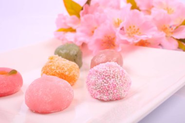 Japon tatlılarının ve açık arkaplanda pembe çiçeklerin yakın plan görüntüsü.        