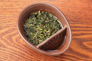 Taze yeşil çay yaprakları kahverengi seramik zerk kabının içinde.