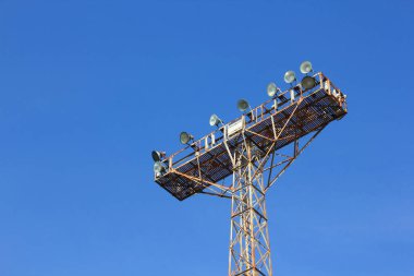 Gökyüzüne karşı çoklu büyük projektörleri destekleyen uzun metal kule