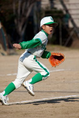 Japon çocuk sahada beyzbol oynuyor.