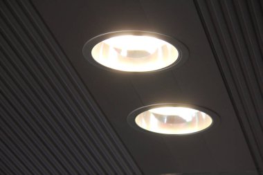 İki parlak tavan lambası koyu çizgili yüzeyi aydınlatıyor.