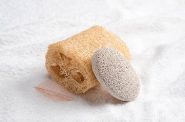 Beyaz havluda duran doğal süngerler ve sünger taşı.