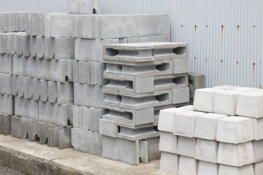 Oluklu metal duvarın yanında istiflenmiş beton bloklar.