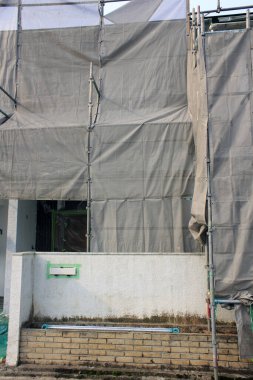 Tamamlanmamış dış duvarı kaplayan gri inşaat brandaları