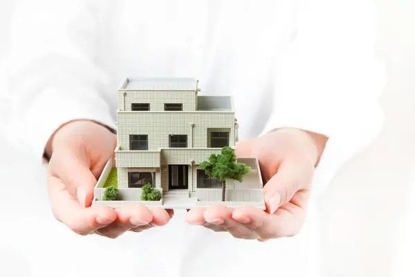 female hands holding small model of house on white background