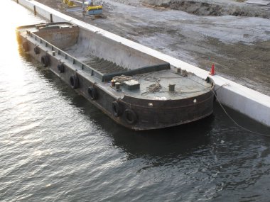 Paslı sanayi mavnası beton iskele duvarının yanında yüzüyor.