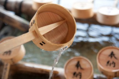 Tahta kepçe geleneksel arıtma çeşmesine su döküyor.