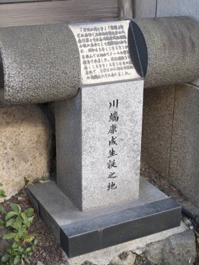 Duvarın yanında Japon harfleri kazınmış granit bir anıt.