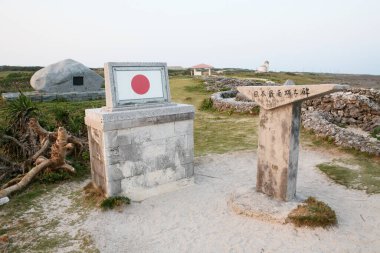 Dışarıda taş güneş saati yakınında Japon bayrağı sergilenen beton bir anıt.