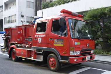 Kırmızı bir itfaiye aracı caddeden geçiyor.