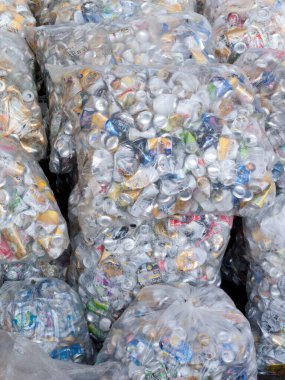 Plastik geri dönüşüm torbalarını dolduran ezilmiş alüminyum kutular.