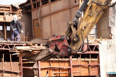Büyük kazıcı, gündüz vakti eski ahşap bina yapısını yıkıyor