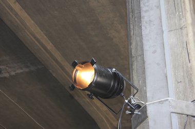 Siyah sahne ışıkları beton tavan yapısına doğru parlıyor.