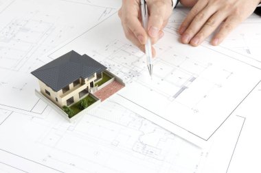 Masasında ev modeli olan bir kalem tutan mimar, yakın plan görünüm             