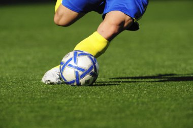 Futbol sahasında mavi arka planlı bir futbolcu