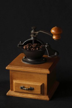 Elinde kavrulmuş fasulye tutan klasik ahşap kahve öğütücüsü.