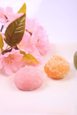 Japon tatlılarının ve açık arkaplanda pembe çiçeklerin yakın plan görüntüsü.        