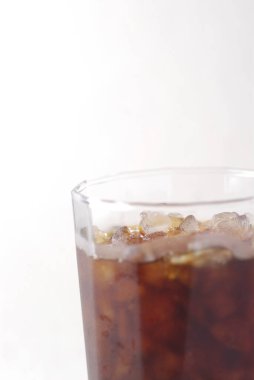 Beyaz arkaplanda buzlu kola bardağı var.