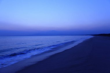 Deniz dalgalarıyla kumsalda güzel bir gün batımı      