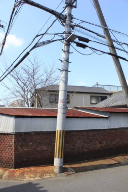 Tuğla duvar ve evin yanında kabloları olan elektrik direği.