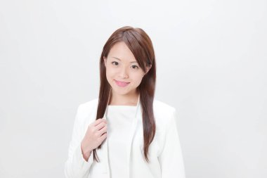 Beyaz arka planda beyaz takım elbiseli şık genç Japon kadın.