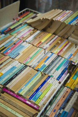 Metal ekran rafında düzgün sıralanmış renkli karton kapaklı kitaplar