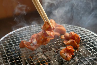Yemek çubuklarıyla ızgarada kızartılmış et yakın plan çekimi.