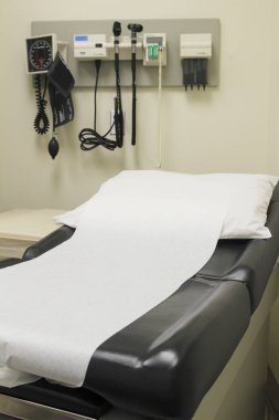 Duvarında yatak ve ekipman olan tıbbi muayene odası.