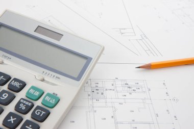 Planların ve hesap makinesinin yakın görüntüsü. Projenin mimari çizimleri            